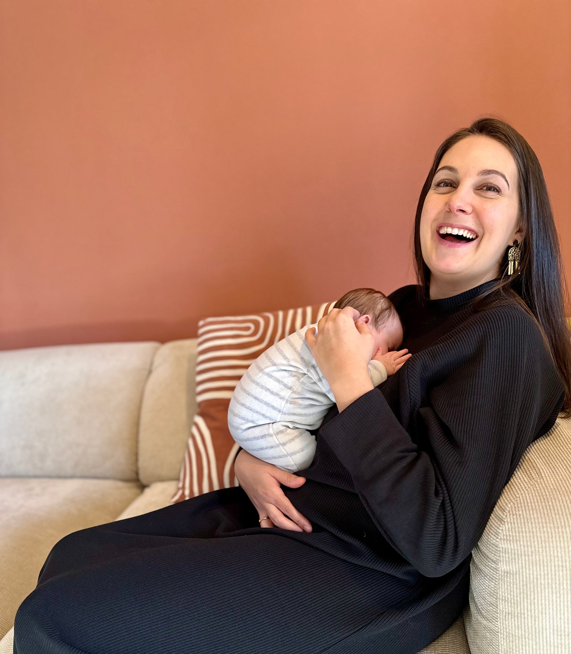 Photo de la marque Nuance lactée, femme souriante avec son bébé portant la robe maille "Singulière" de couleur noir. Robe d'allaitement